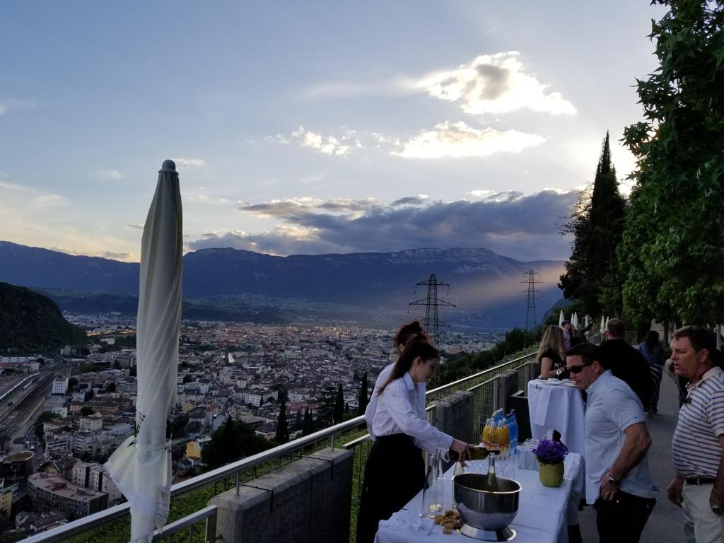 Scenic view of a Tyrolean Dinner in Bolzano as the sun sets over the city and mountains.