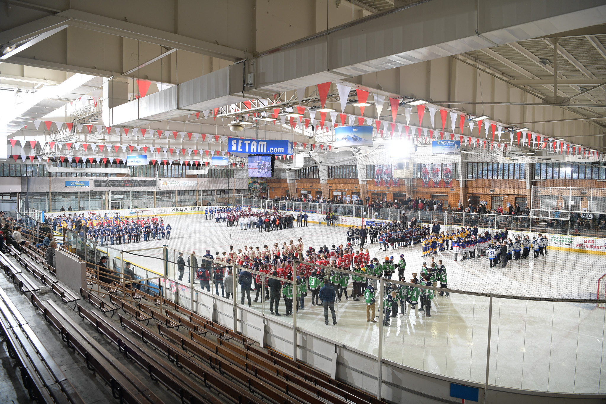 A wide angle shot of an ice rink with various teams on the ice for opening ceremonies at the World Selects Invitational Trophy Tournament.