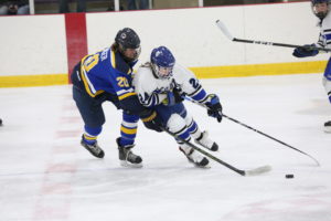A hockey player from Team Illinois fends off a defender from the St. Louis AAA Blues at center ice during a game.