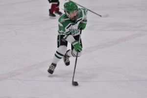 A hockey player from Dallas Stars Elite skates up the ice with the puck on his stick during a game.