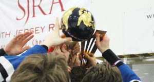 The World Selects Invitational Trophy is hoisted into the air while a team of hockey players reach for it.