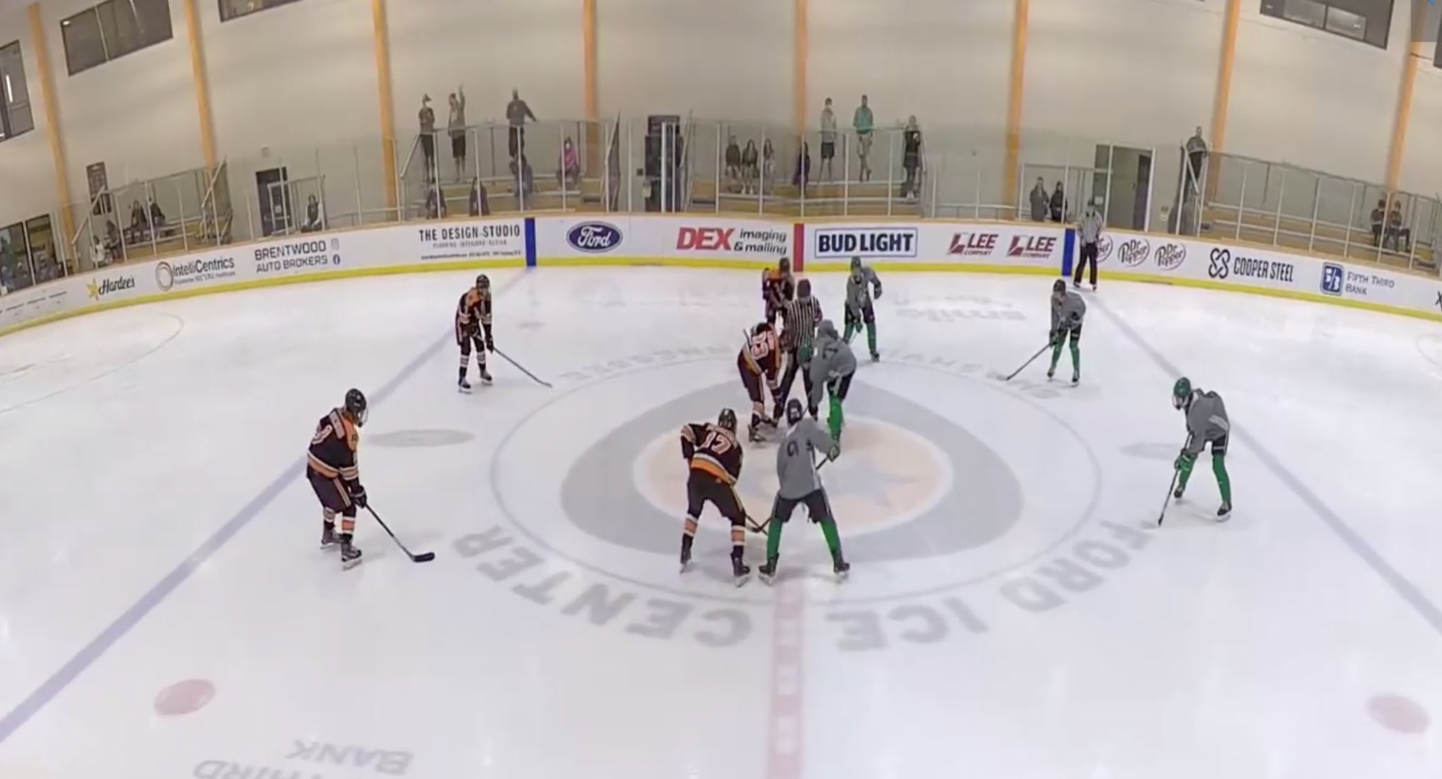 A wide angle shot of two youth hockey teams lined up for a center ice face-off.