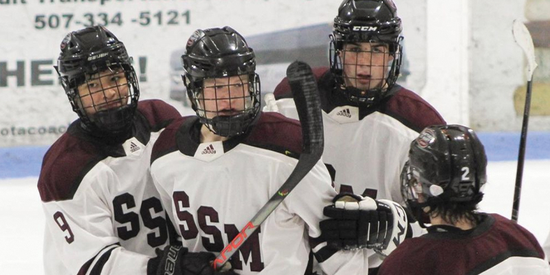 Shattuck-St. Mary's players celebrate on the ice after scoring a goal.