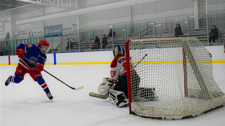 Girls youth hockey player from the Chicago Young Americans shoots a puck past the goaltender on a breakaway.