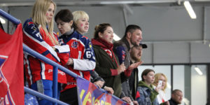 Parents lined up in the front row at a hockey game cheering on the CSKA Moscow team.