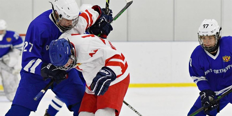 Two Russian youth hockey players tied up with each other while battling for a loose puck.