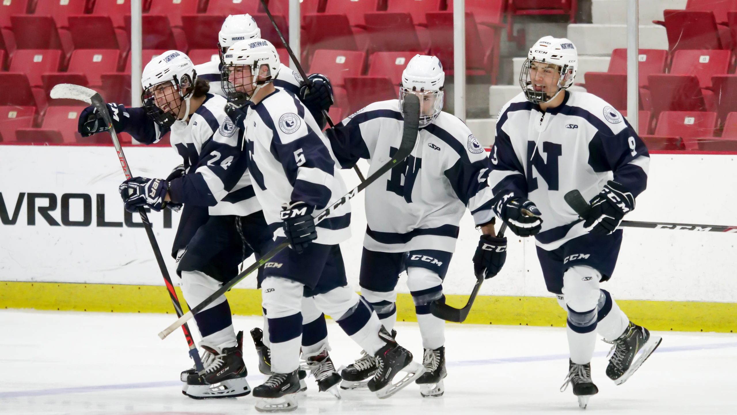 Five hockey players from Nichols School celebrate after scoring a goal.
