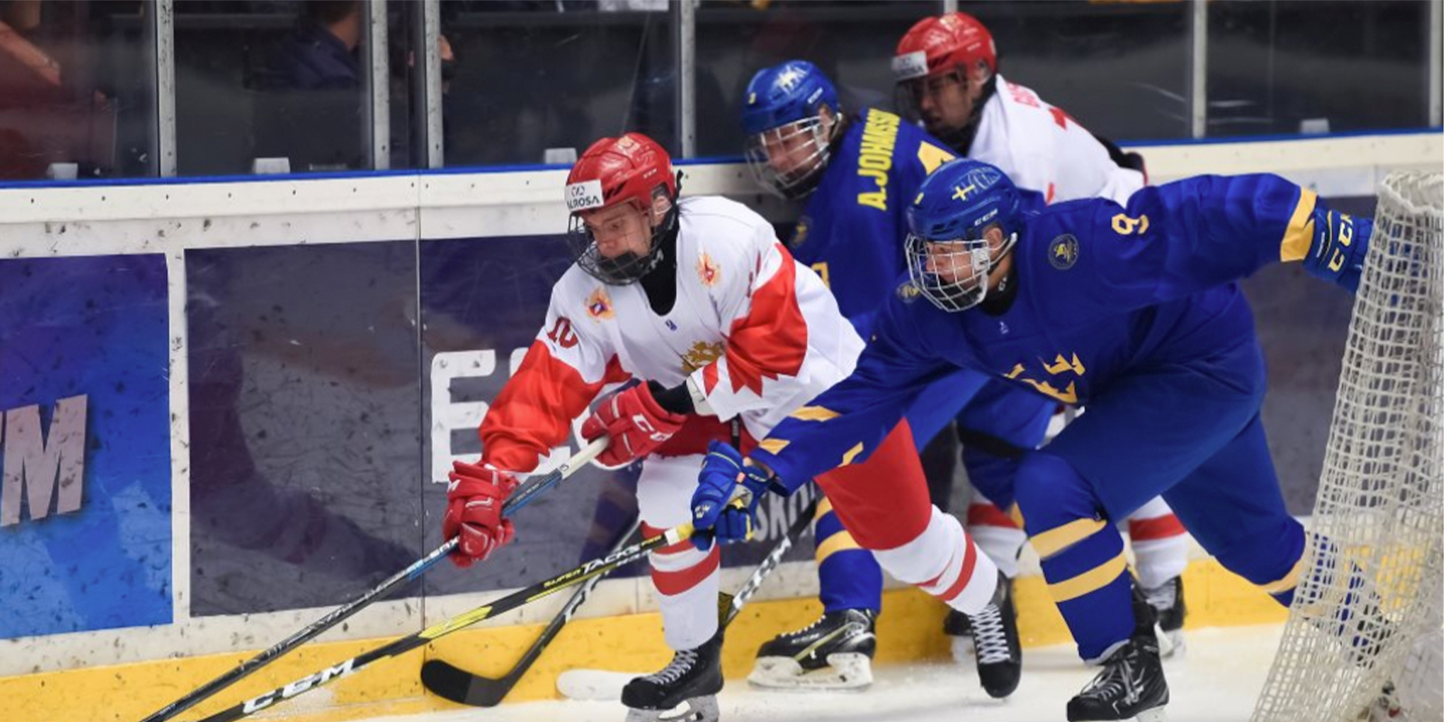 A player from Sweden battles a player from Russia for possession of the puck at the U18 World Junior Championships.