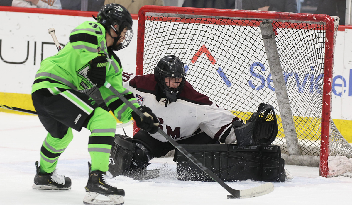 Chicago Mission skater attempts to put a puck past Shattuck-St. Mary's goaltender
