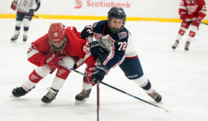 Youth hockey players from the Toronto Jr. Red Wings and Mississauga Rebels battle for a loose puck.